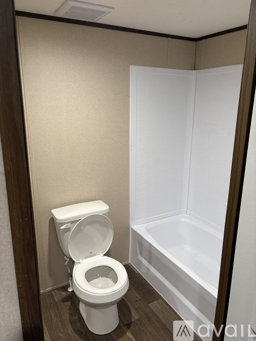 A white toilet is in a small bathroom with a white bathtub.