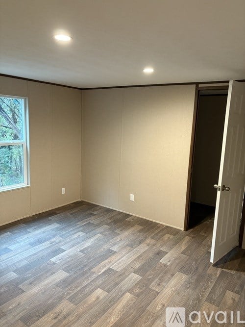 A room with a wooden floor and a door on the right side.