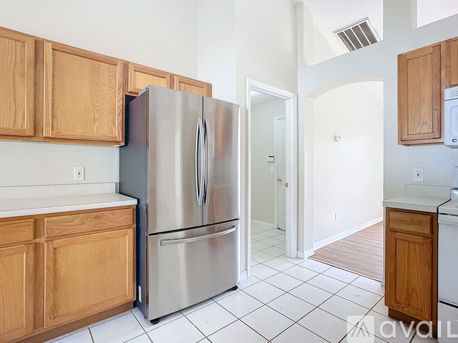A kitchen with a stainless steel refrigerator and wooden cabinets.