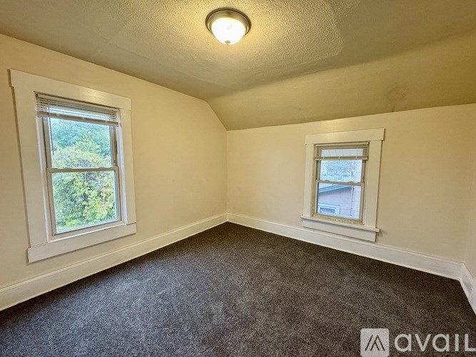 A room with two windows and carpeted floor.