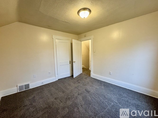 A room with a carpeted floor and two doors.