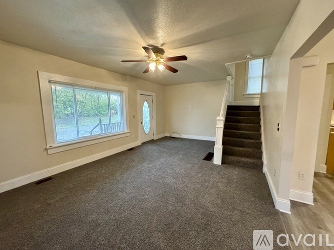 A room with a ceiling fan and a staircase.