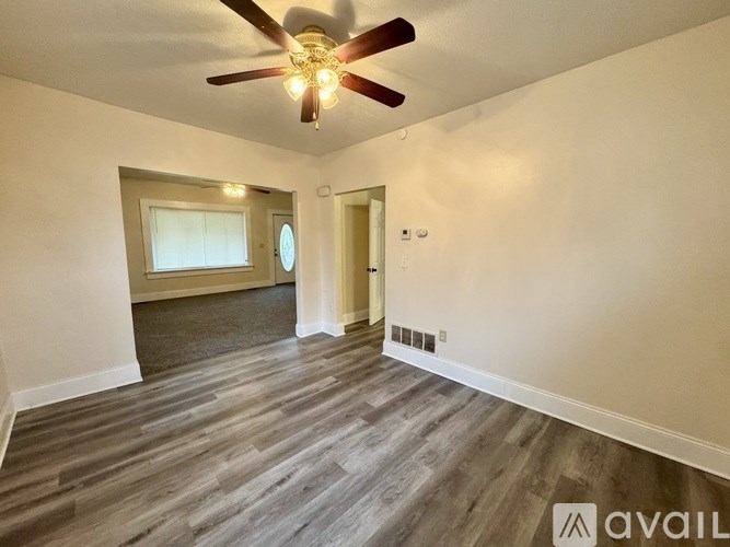 A room with a ceiling fan and wooden flooring.