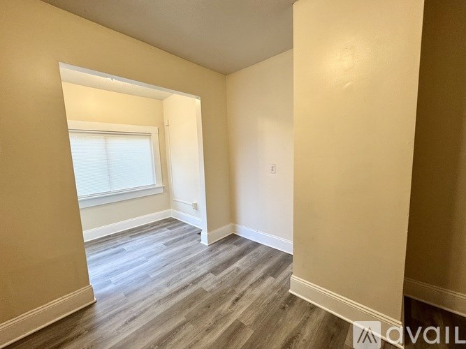 A room with a window and wooden flooring.