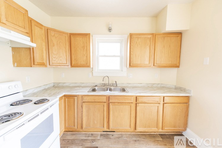 A kitchen with wooden cabinets and a white stove top oven.