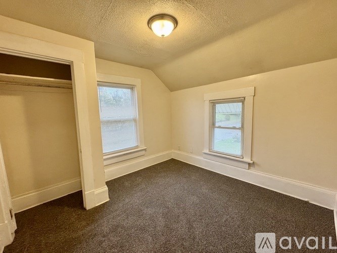 A room with a carpeted floor, a window, and a door.