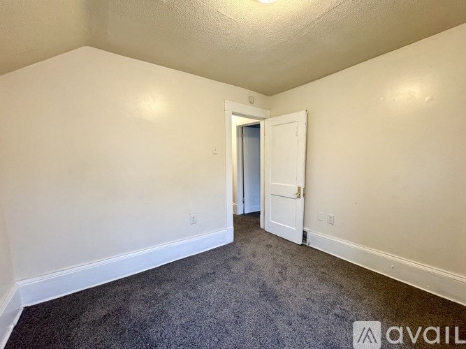 A room with a carpeted floor and a doorway leading to another room.