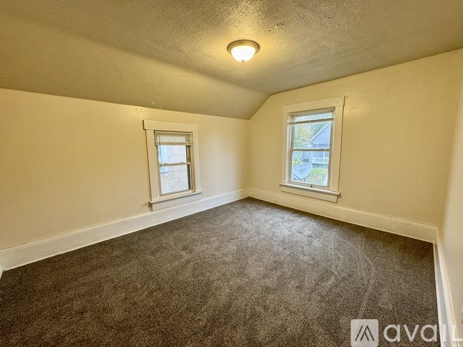 A room with carpeted floor and two windows.