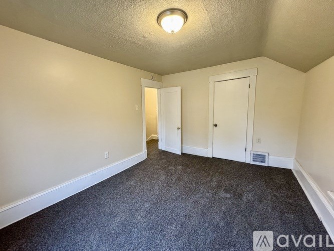 A room with a carpeted floor and two doors.
