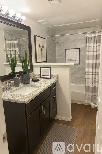 A bathroom with a marble countertop and a mirror above it.