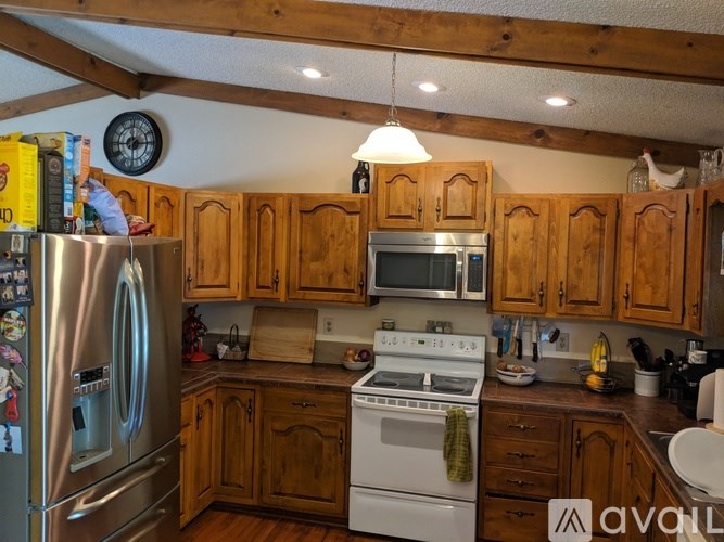 A kitchen with wooden cabinets and a stainless steel refrigerator.