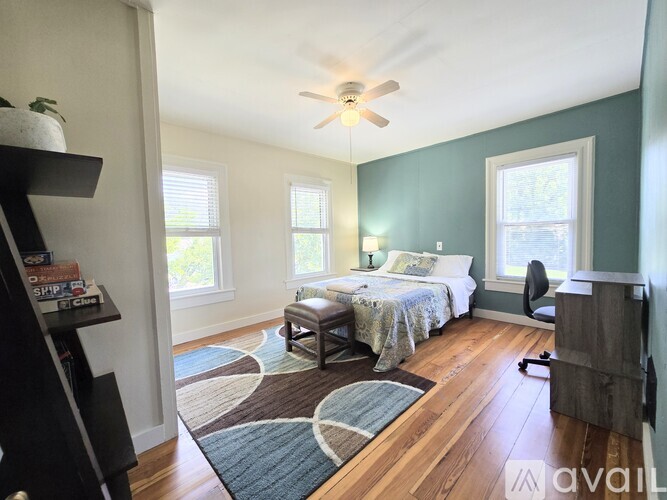A bedroom with a bed, a chair, and a ceiling fan.