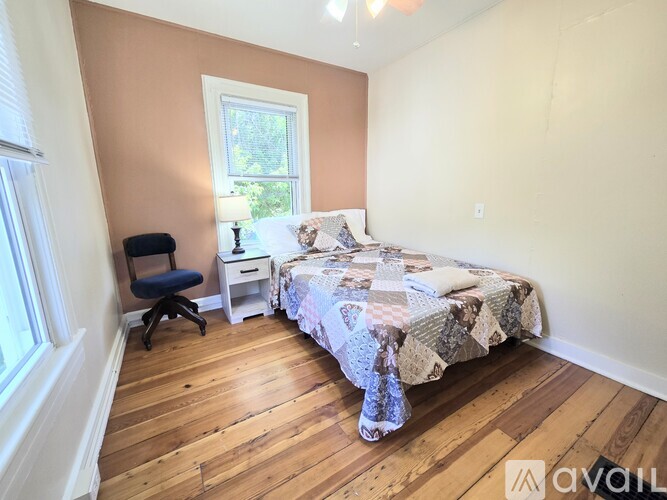 A bedroom with a bed, chair, and window.