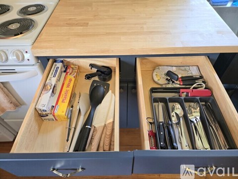 A kitchen drawer with utensils and a spoon in it.
