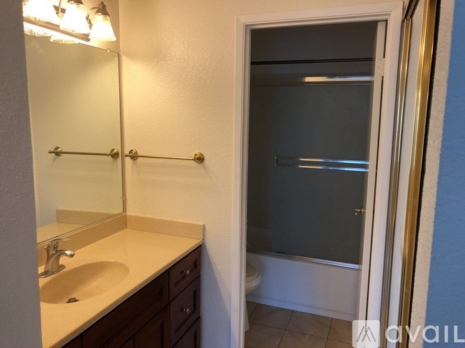 A bathroom with a sink, mirror, and shower.
