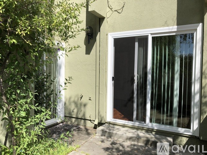 A white door with a glass window is on the right side of a green building.