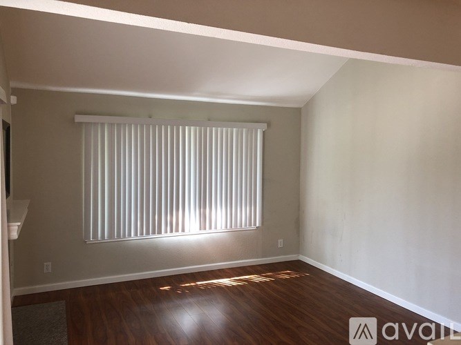 A room with wooden floors and a window with blinds.