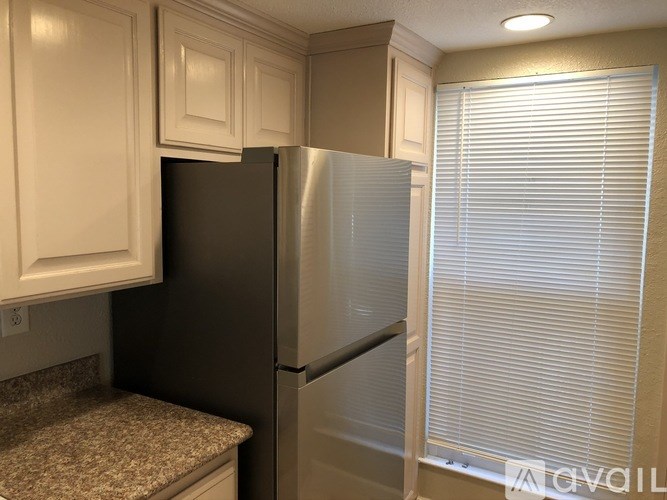 A kitchen with a black refrigerator and white cabinets.
