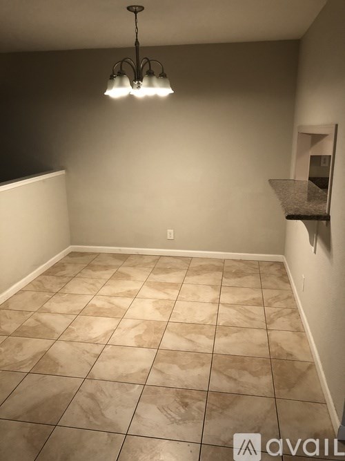 A room with tiled flooring and a hanging light fixture.