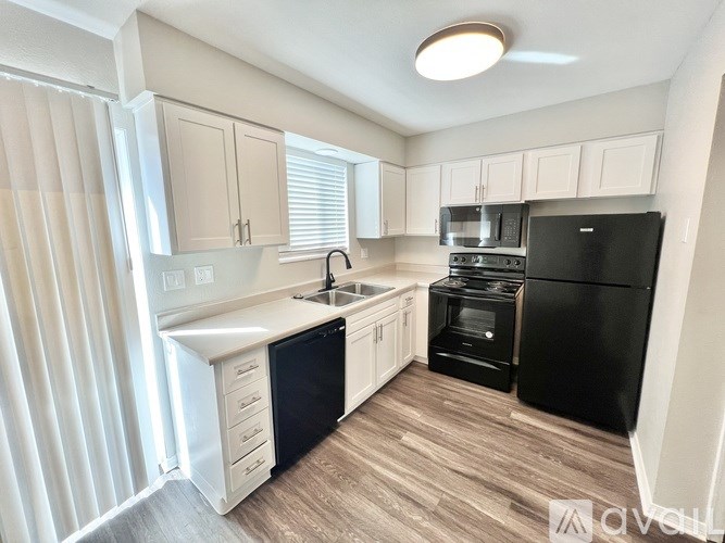 A kitchen with black appliances and white cabinets.
