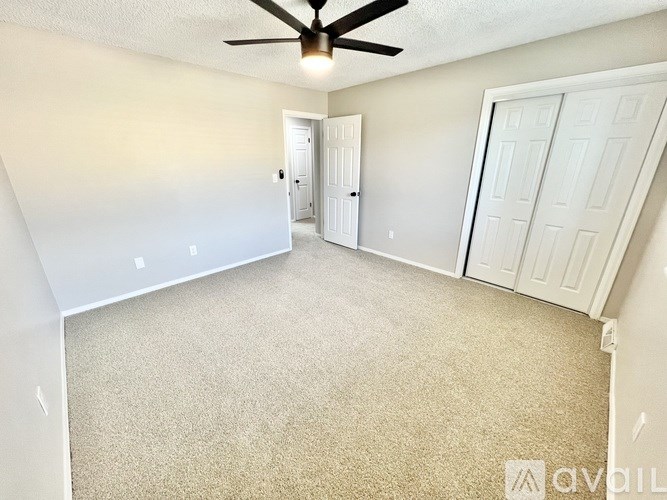 A room with a ceiling fan and two doors.