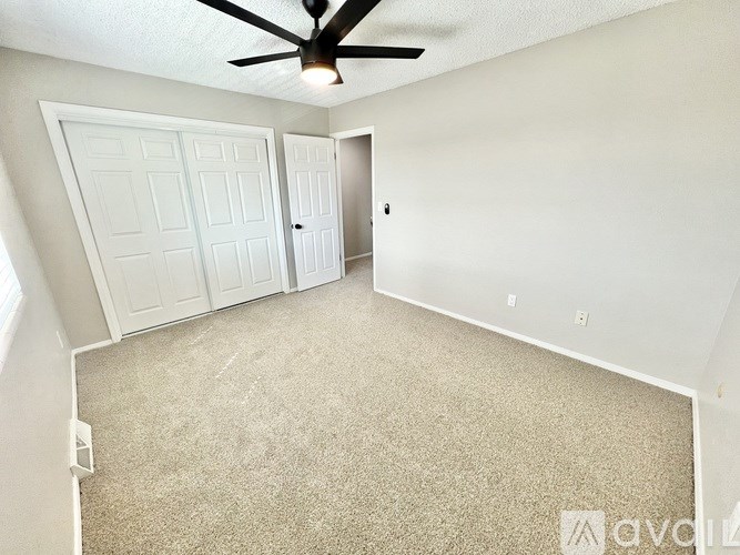A room with a ceiling fan and carpeted floor.