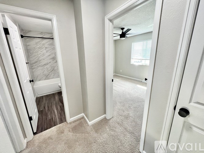 A carpeted room with a door and a fan.