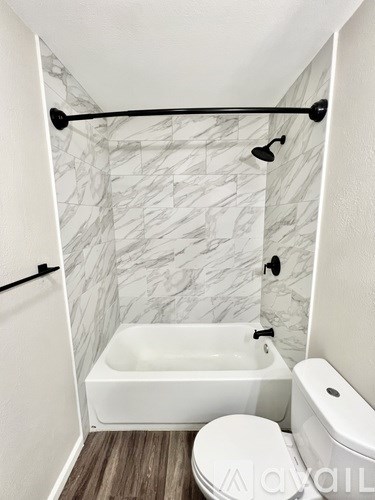 A white bathroom with a marble wallpaper and a white tub.