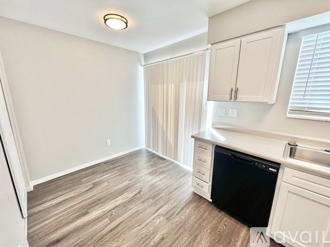 A kitchen with a black dishwasher and white cabinets.