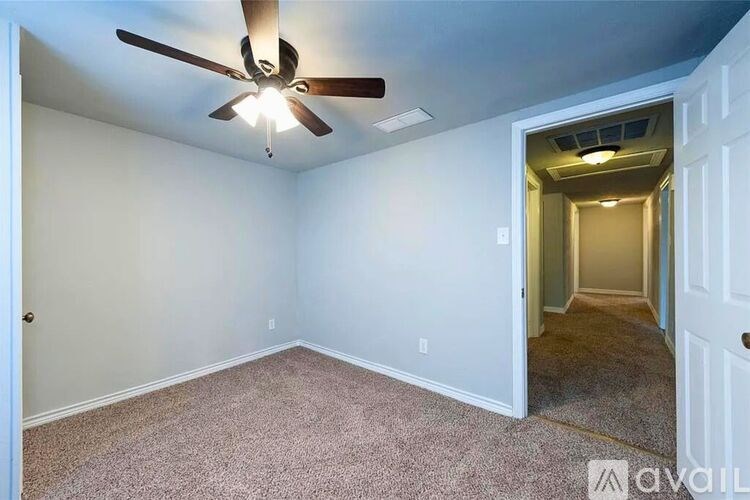 A room with a ceiling fan and carpeted floor.