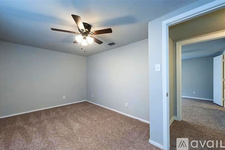A room with a ceiling fan and carpeted floor.