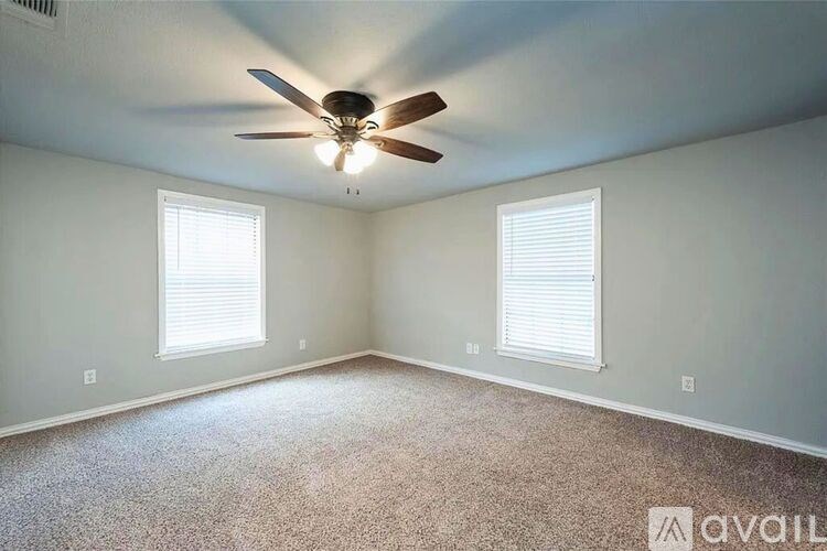 A room with a ceiling fan and two windows.