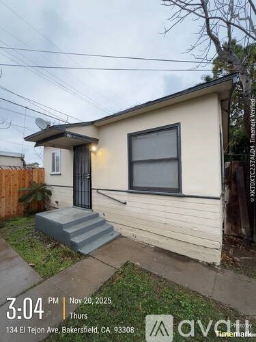 A small house with a black gate and a window with a light on.