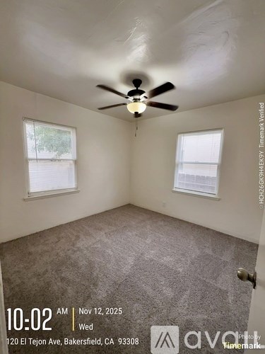 A room with a ceiling fan and two windows.