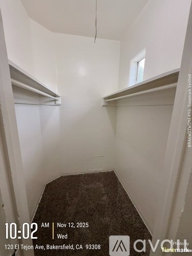 A room with a window and a shelf in the corner.