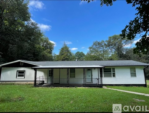 A house with a porch and a tree in front.