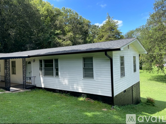 A small white house with a black roof and a porch.