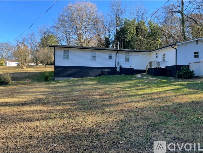 A white house with a black roof is surrounded by a grassy field.
