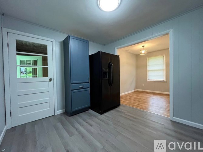 A kitchen area with a black fridge and a white door.
