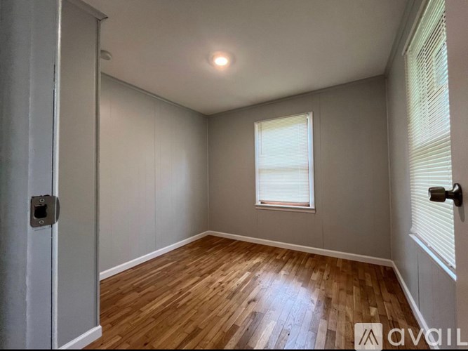 A room with wooden flooring and a window with blinds.