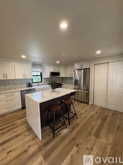 A kitchen with a white island and wooden floors.