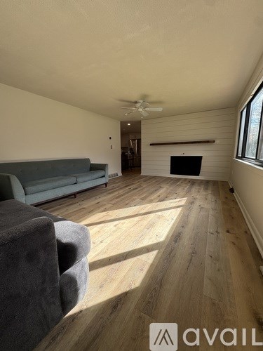 A living room with a grey couch and wooden flooring.