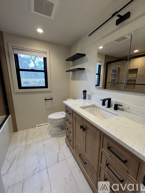 A bathroom with a toilet, sink, and mirror.