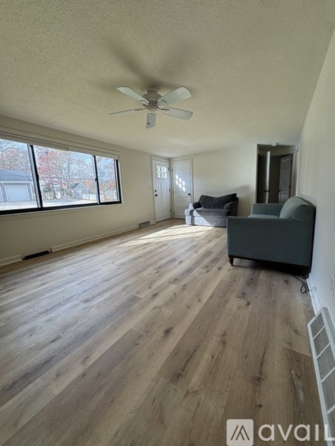A living room with a grey couch and a ceiling fan.