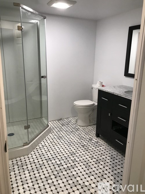 A white toilet sits in a bathroom with a black and white floor.