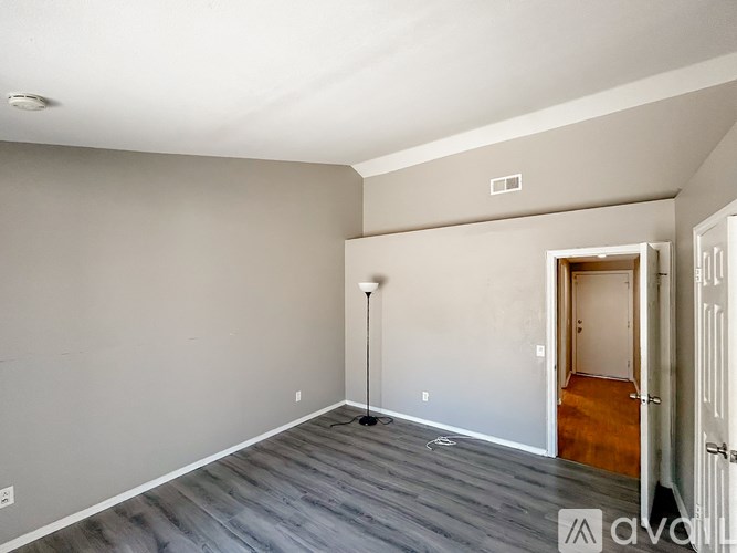 A room with grey walls and wooden flooring is available for rent.
