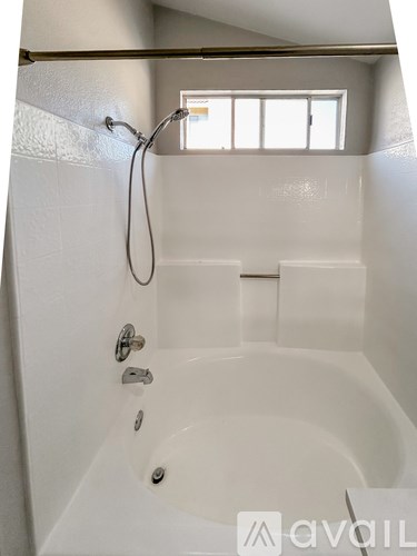A white bathtub with a shower head and faucet.