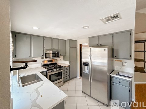 A kitchen with a white counter top and stainless steel appliances.