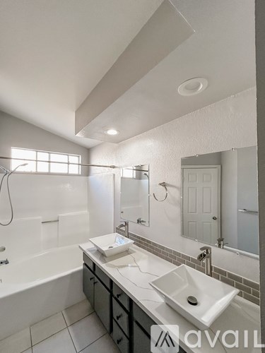 A bathroom with a white tub, sink, and mirror.