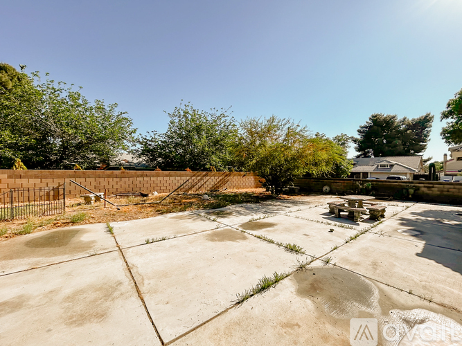 A concrete area with a fence and trees in the background.